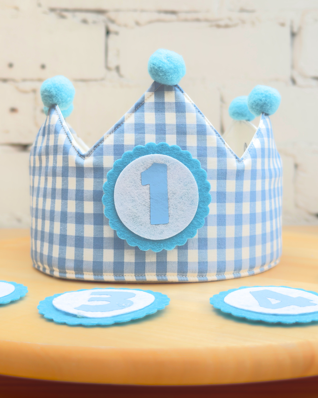 Cara reversible en vichy azul de la corona de cumpleaños, con pompones azules y el número 1