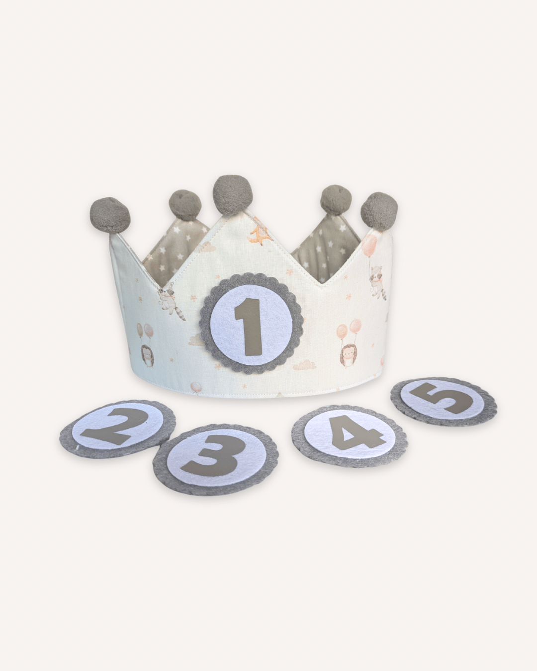 Corona de cumpleaños con estampado de globos en azul y pompones grises, con los números intercambiables del 1 al 5